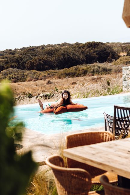 Woman enjoying a sunny day on a pool float in Greece's countryside.