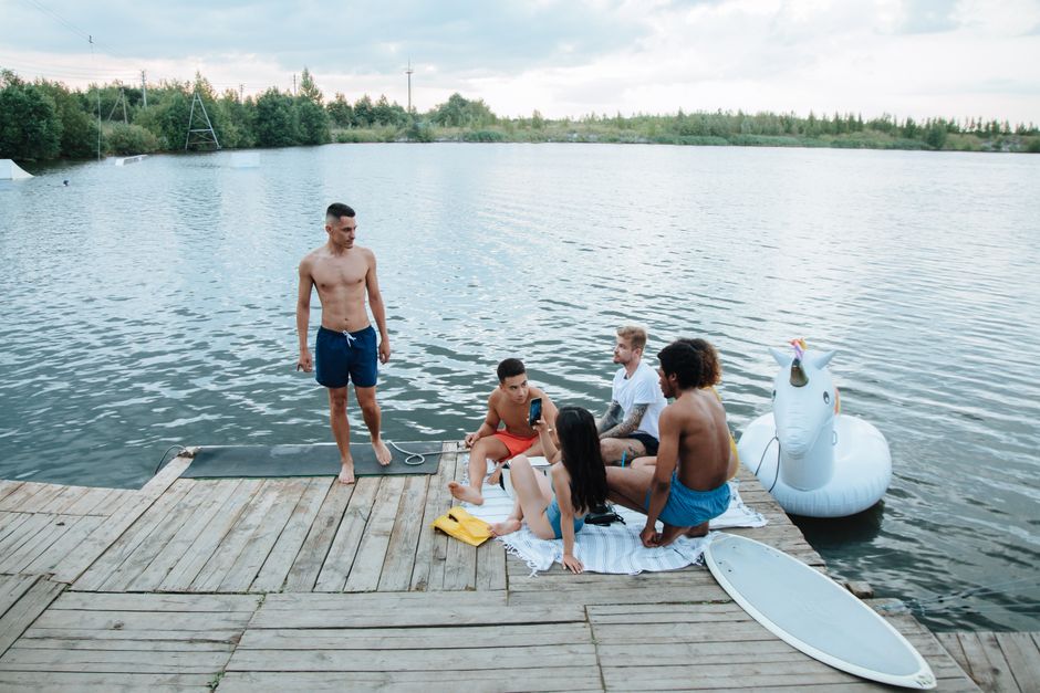 A group of friends enjoying a summer day by the lake with an inflatable unicorn.