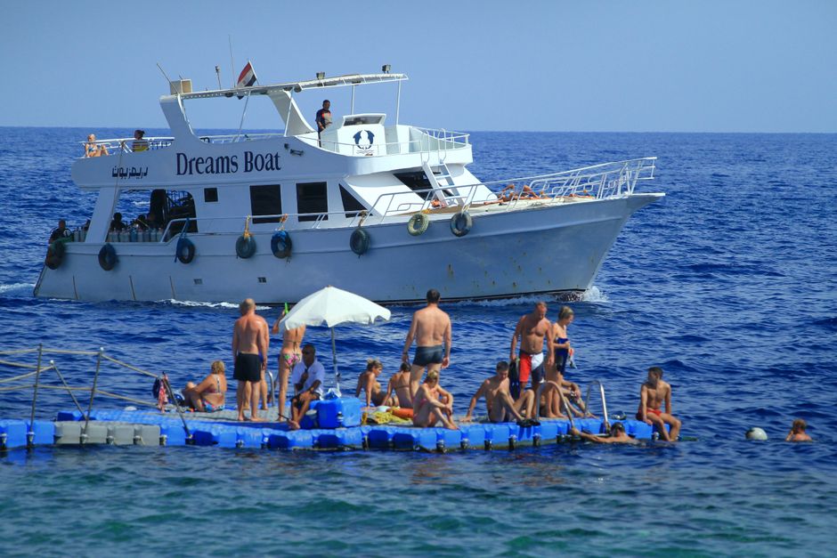 People enjoying sunny day on floating platform by boat.